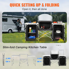 Black aluminum folding camping kitchen table with storage bags and utensil hooks outdoors.