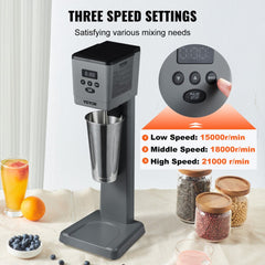 Gray Bostome electric milkshake maker with 3-speed digital display, stainless steel cup, and base on a table with fruits and ingredients.