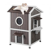 Cedar wood 2-story outdoor cat house with triangular roof and large double-sided doors.