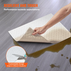 Hand holding a white perforated oil absorbent pad on a wet floor, showing its absorbent side.