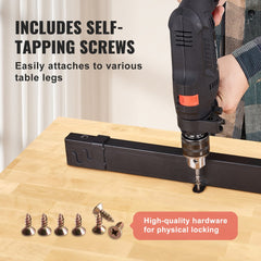 A person uses a drill to attach a black metal frame to a maple wood desktop with screws.