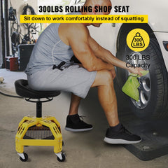 A man sits on a yellow adjustable-height rolling garage stool with 300 lbs capacity, working on a car tire.