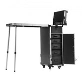 Black aluminum rolling makeup trolley case with open drawers, fold-out table, and wheels.