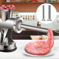 Silver manual meat grinder with sausage attachment on counter, showing ground meat and sausage.