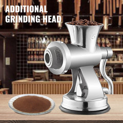 Stainless steel manual meat grinder with coffee beans in the hopper and ground coffee on a plate.