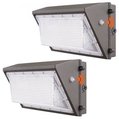 Two gray 100W LED wall pack lights with white diffusers, motion sensors, and dusk-to-dawn photocells.