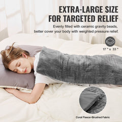 A woman lies in bed using a gray 17x33-inch weighted heating pad filled with ceramic beads for relief.
