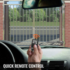 Hand holding remote control inside car facing a metal dual swing gate opener system.