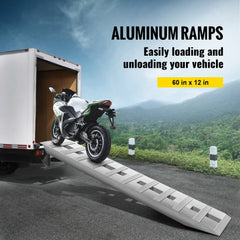 Aluminum trailer ramps with serrated rungs supporting a motorcycle loading into a truck bed.