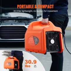 Orange portable 1 HP dual-cylinder refrigerant recovery machine, 30.9 lbs, with power cord, held by person near car.