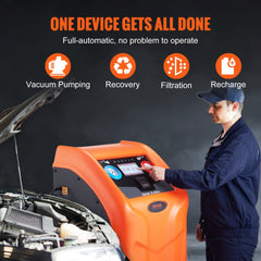 Orange fully automatic dual-cylinder refrigerant recovery machine connected to a car engine bay, with a technician operating its touchscreen.