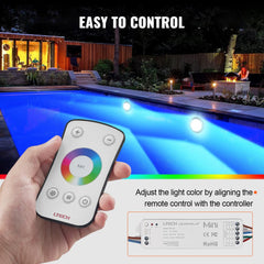 Hand holding RF remote aligned with RGBW LED pool light controller near illuminated inground pool at night.