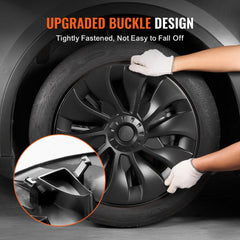 A person installs a black 18-inch wheel rim cover on a Tesla Model 3 tire.