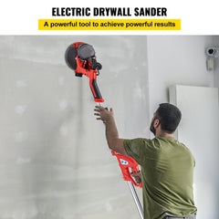 Man using red 850W electric drywall sander with foldable handle on white wall.
