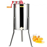 Stainless steel manual honey extractor with red handle and adjustable tripod stand, next to honey jar and comb.