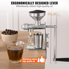 Stainless steel manual oil press machine with ergonomic lever and detachable parts on a wooden table.