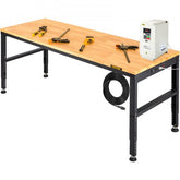A long, light wood workbench with black adjustable legs holds various tools and a power inverter.