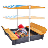 Wooden sandbox with blue-striped canopy, benches, and child playing in sand.