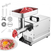 Silver stainless steel electric meat grinder with accessories and ground meat on plate.