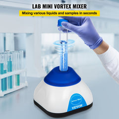 Compact blue and white mini vortex mixer on a lab bench, with a hand in blue gloves holding a test tube that activates the swirling motion.