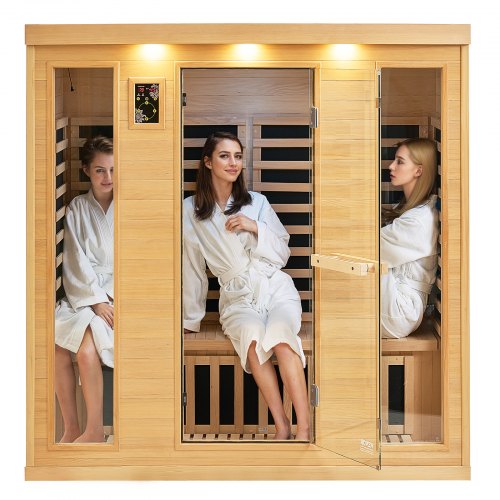 Wooden infrared sauna room with glass door and three people inside wearing white robes.