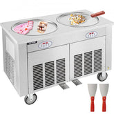 Double pan ice cream machine with stainless steel construction and caster wheels for mobility.