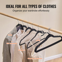 Black velvet hangers holding coats, pants, silk garments, sweaters, and camisoles on a wooden rod.