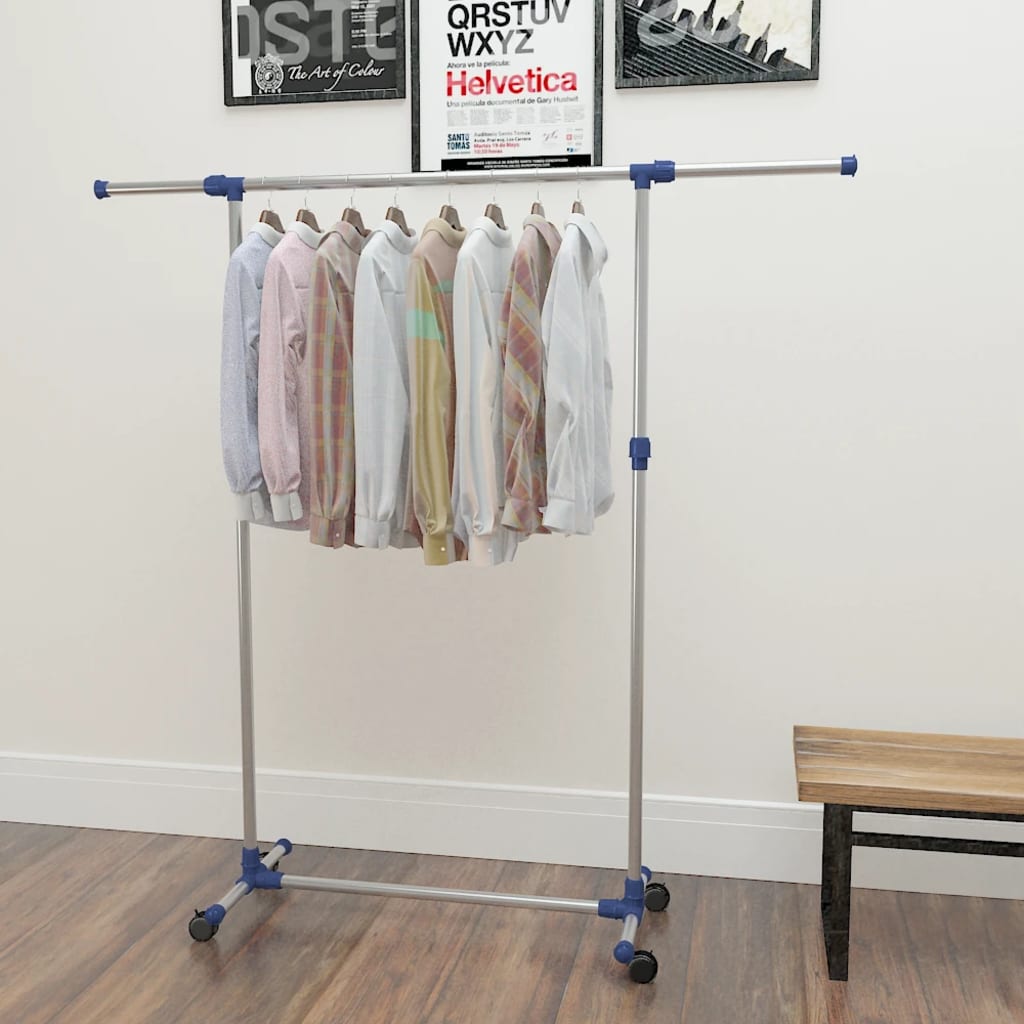 Silver adjustable stainless steel clothes rack with clothes hanging, on wheels and wood floor.