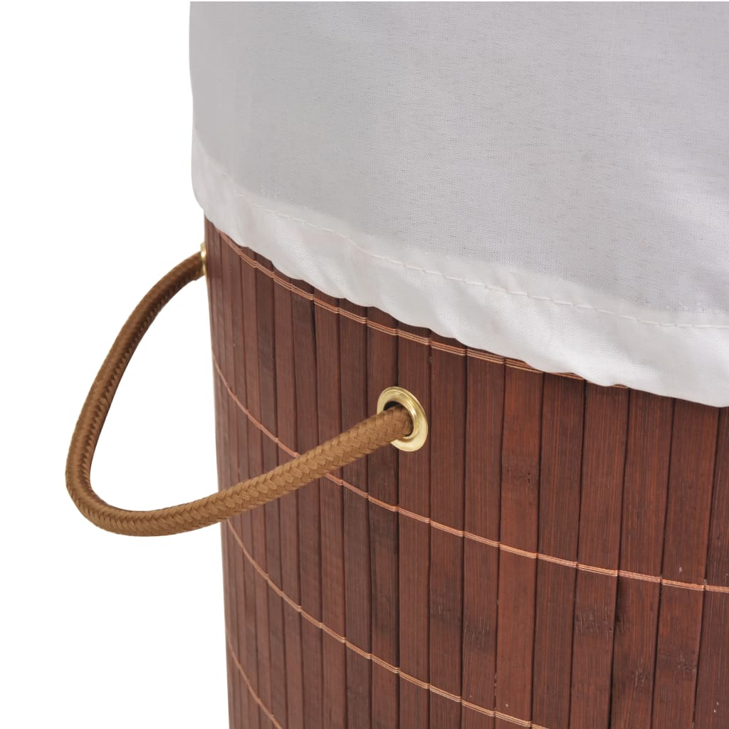 Brown bamboo round laundry hamper with white liner and leather handles.