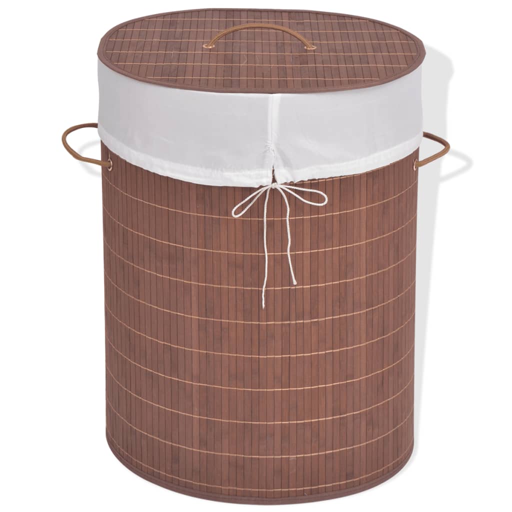 Oval brown bamboo laundry hamper with white woven liner and leather handles.