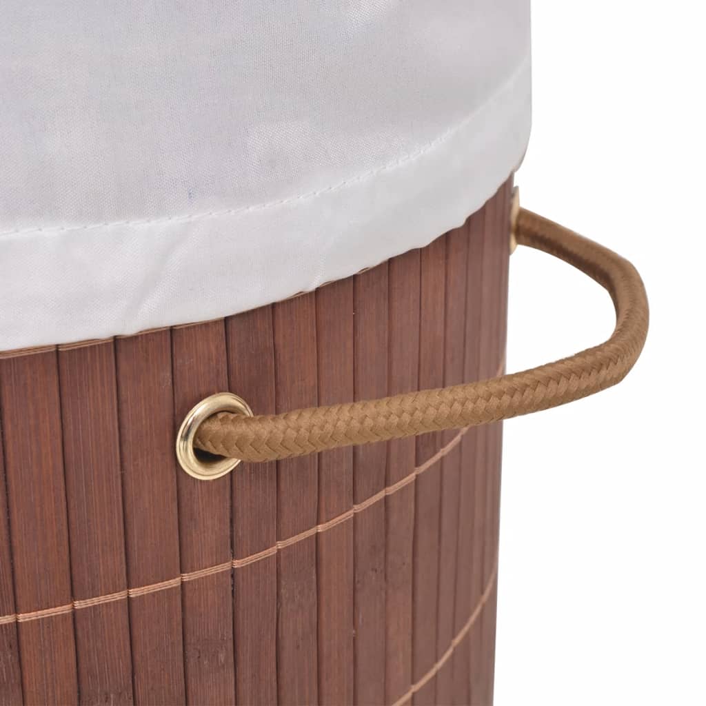 Oval brown bamboo laundry hamper with white liner and rope handles.