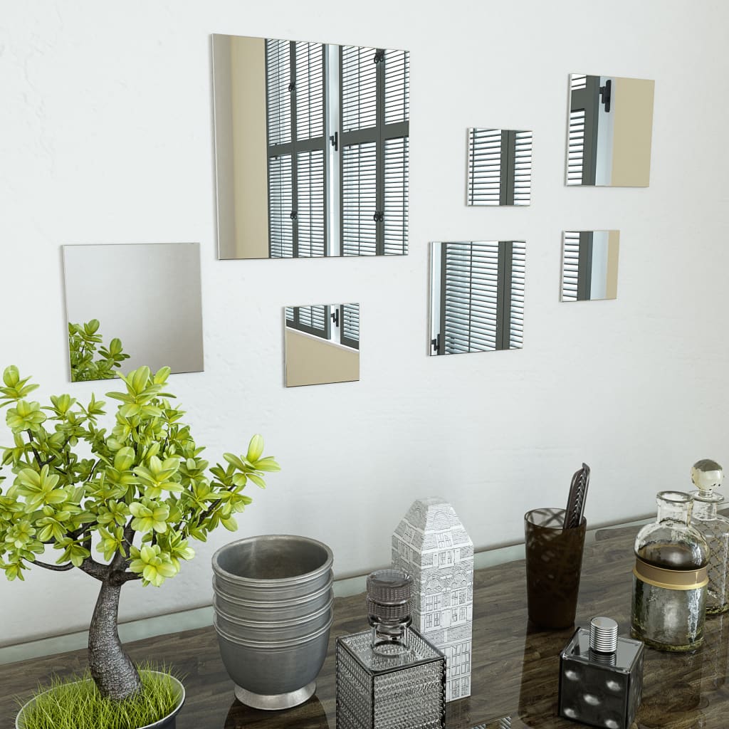 Seven square frameless glass mirrors in varying sizes arranged on a white wall.