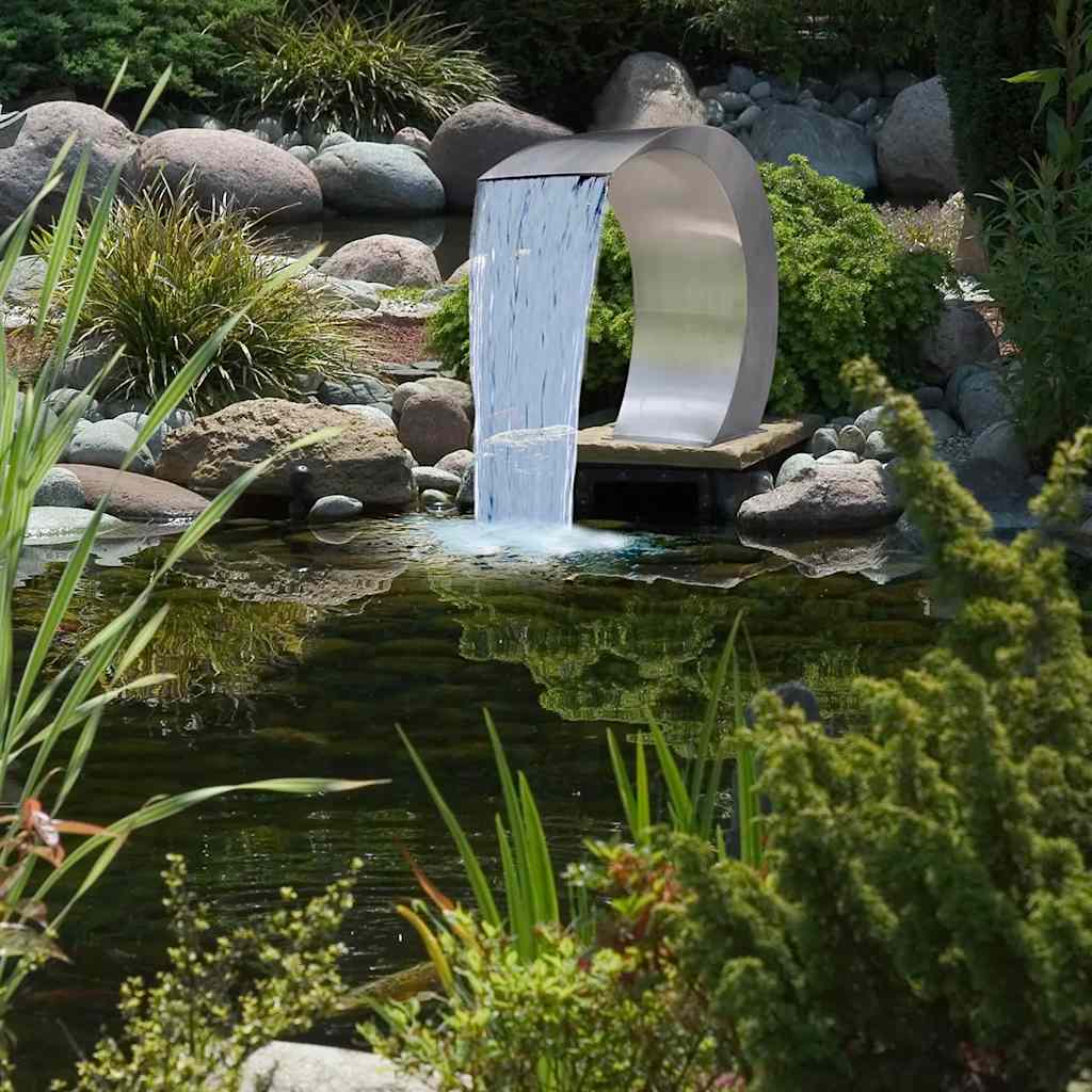 Stainless steel garden waterfall fountain cascading into a pond with rocks and plants.