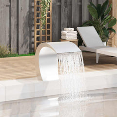 A stainless steel garden waterfall fountain cascades water into a pool on a wooden deck beside a lounge chair.