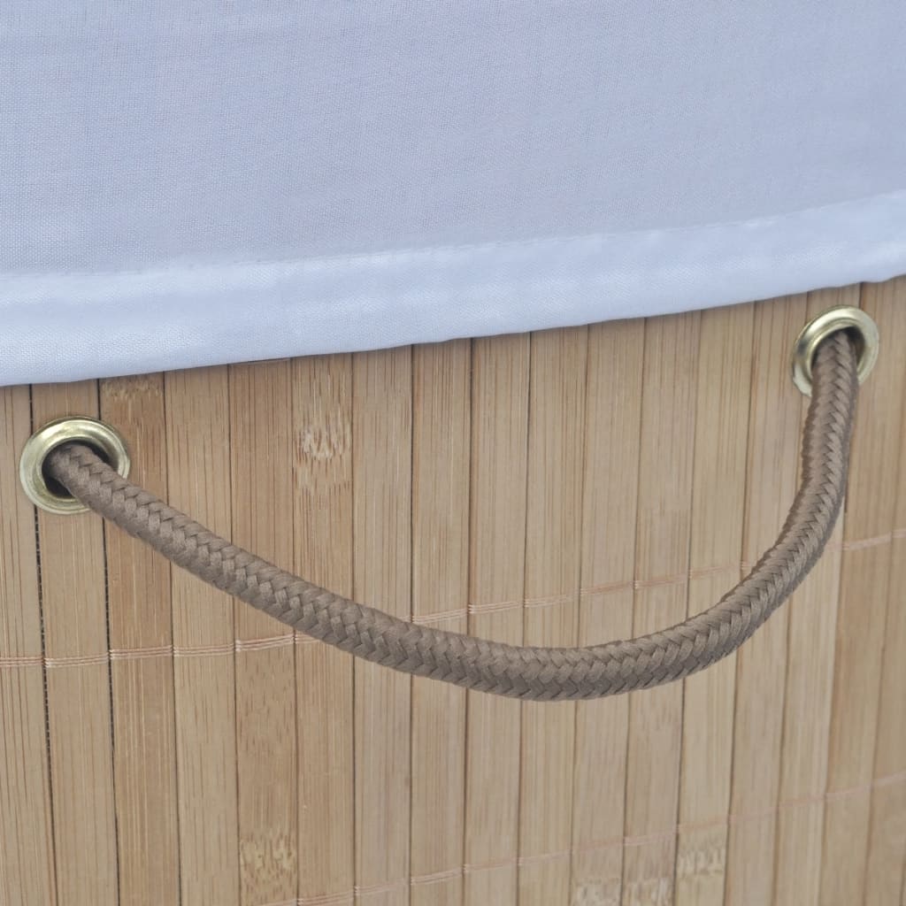 Oval natural bamboo laundry hamper with brown rope handles and white liner.