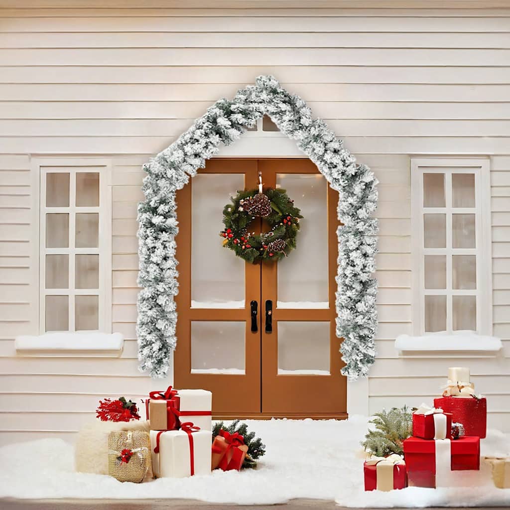 16 ft flocked snow green PVC Christmas garland draped over a white house door with wreath and gifts.