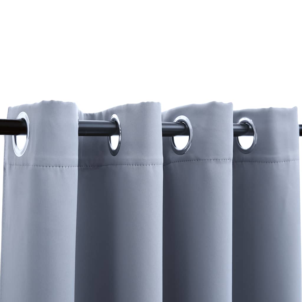 Two gray blackout curtain panels with metal rings are shown on a dark rod.