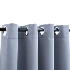 Two gray blackout curtain panels with metal rings are shown on a dark rod.