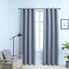 Two gray blackout curtain panels, 54x84 inches each, with rings, hanging on a window.