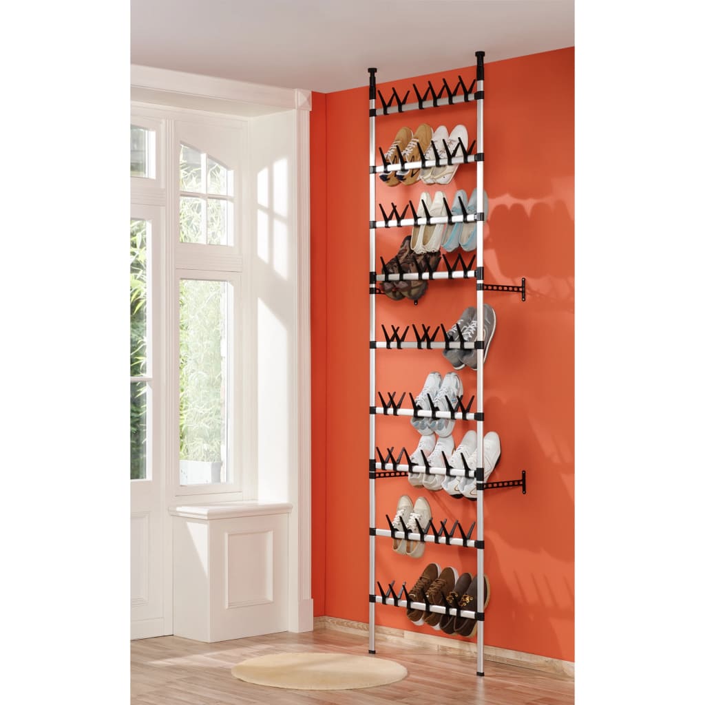 Silver and black telescopic aluminum shoe rack with rods, holding multiple pairs of shoes against a wall.