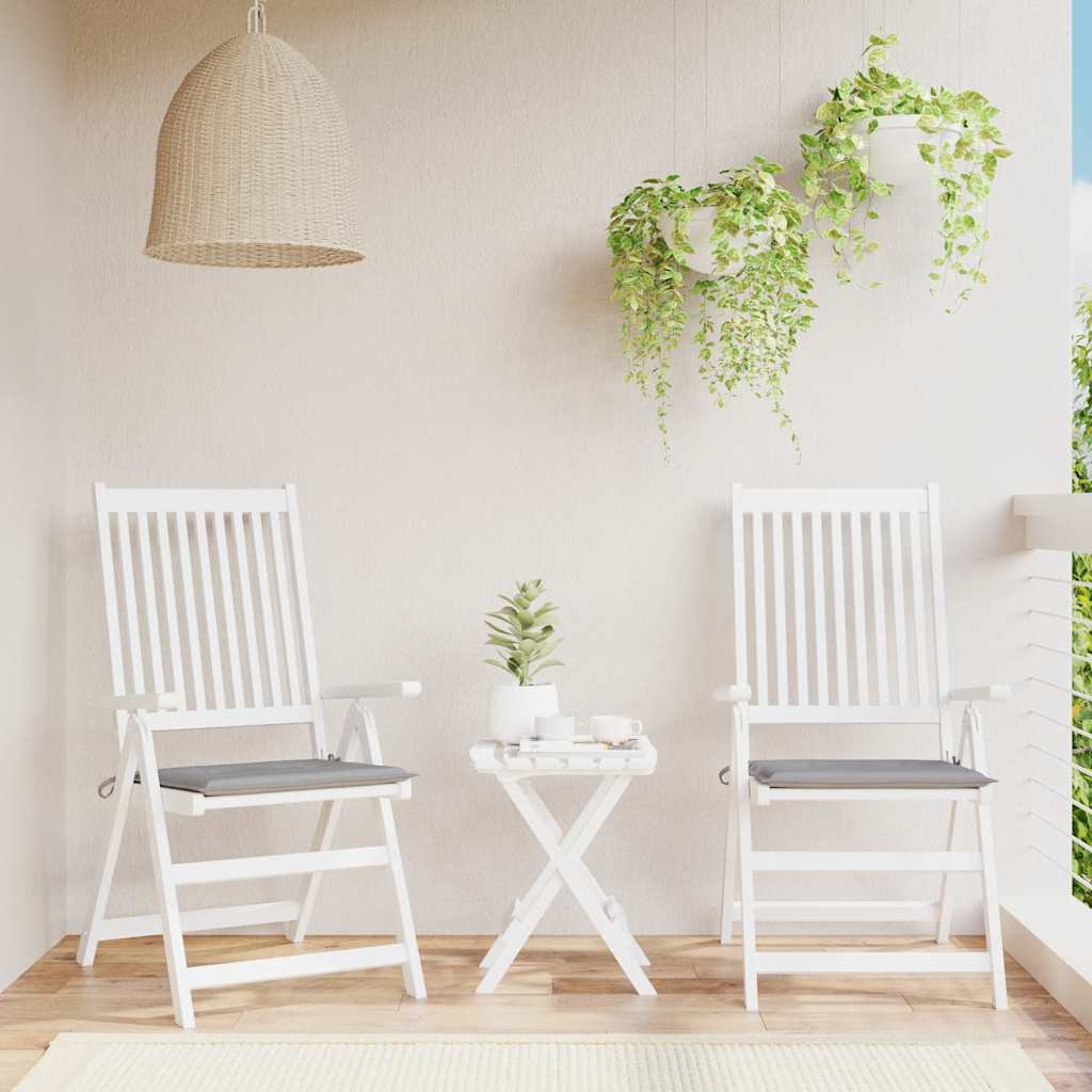 Two gray Oxford fabric garden chair cushions with ties on white wooden chairs on a balcony.