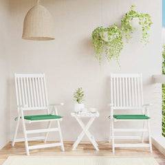 Two green Oxford fabric chair cushions on white folding patio chairs with a small table.