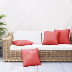 Four red polyester throw pillows, 23.6x23.6 inches, on a white wicker patio sofa.