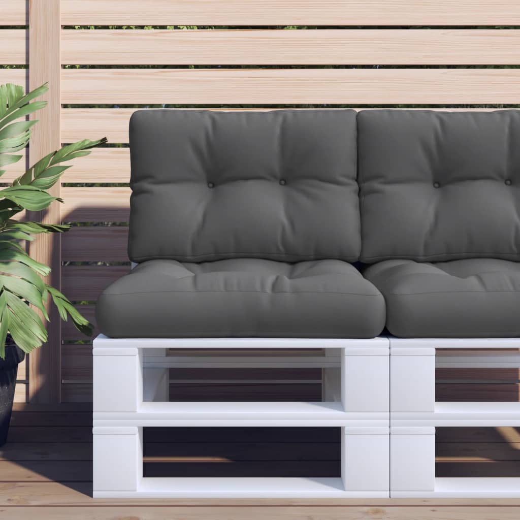 Two anthracite polyester cushions on a white pallet sofa against a wooden fence.