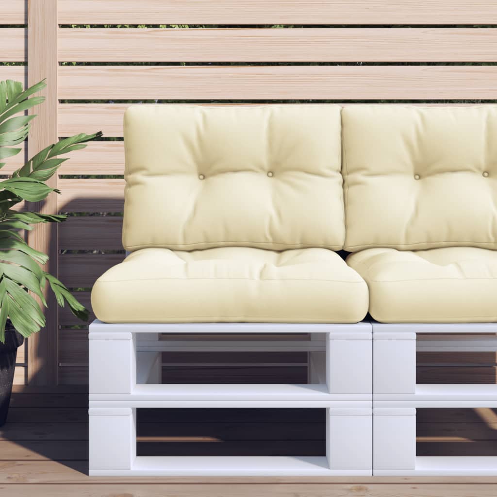 Two cream polyester pallet cushions are on a white pallet sofa on a wooden deck.