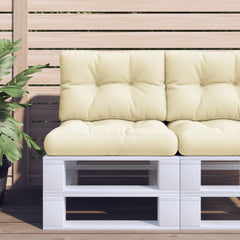 Two cream polyester pallet cushions are on a white pallet sofa on a wooden deck.
