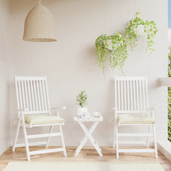 Two cream white outdoor chair cushions on white folding chairs with a small table on a balcony.