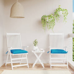 Two light blue Oxford fabric chair cushions on white patio chairs with a small table.