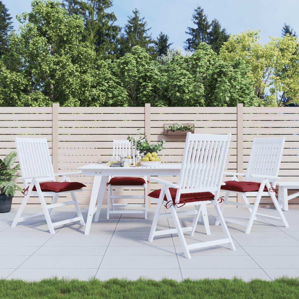 Four wine red Oxford fabric chair cushions with red ties on white patio chairs.
