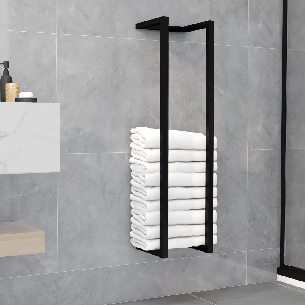 Black iron towel rack with four rungs holding stacked white towels on a gray bathroom wall.